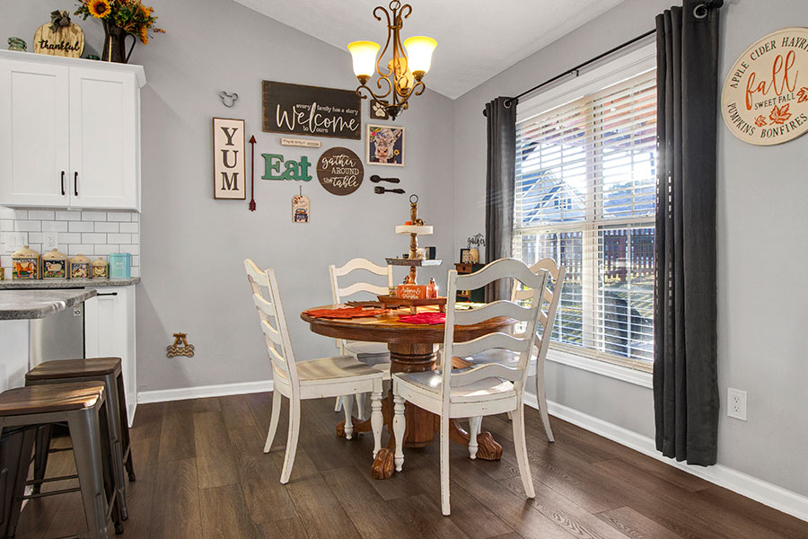 Modern Acworth, GA home featuring a stylish kitchen and dining area with sleek white cabinets, elegant granite countertops, and rich hardwood flooring, creating a warm and inviting atmosphere.