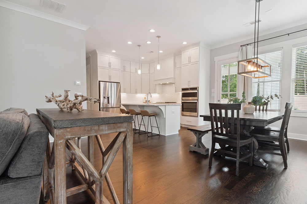 Spacious great room with vaulted ceilings, elegant white fireplace, custom built-in shelves, and hardwood flooring in a luxury Atlanta home.